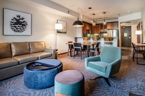 Una sala de estar moderna con sofá, reposapiés, sillón y un comedor con sillas y una mesa.