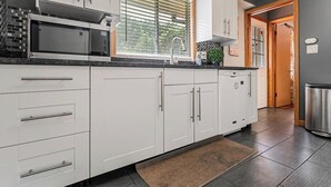 A modern kitchen with white cabinets, a built-in microwave, and a window with blinds. - Fairlawn 327 | 6 BR • 2F & 4H Bathrooms (Fairlawn)
