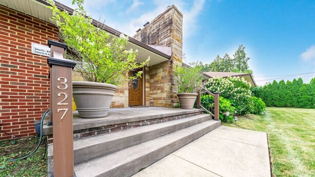 A brick building with a stone tower, a large potted plant, and a sign indicating security cameras. - Fairlawn 327 | 6 BR • 2F & 4H Bathrooms (Fairlawn)