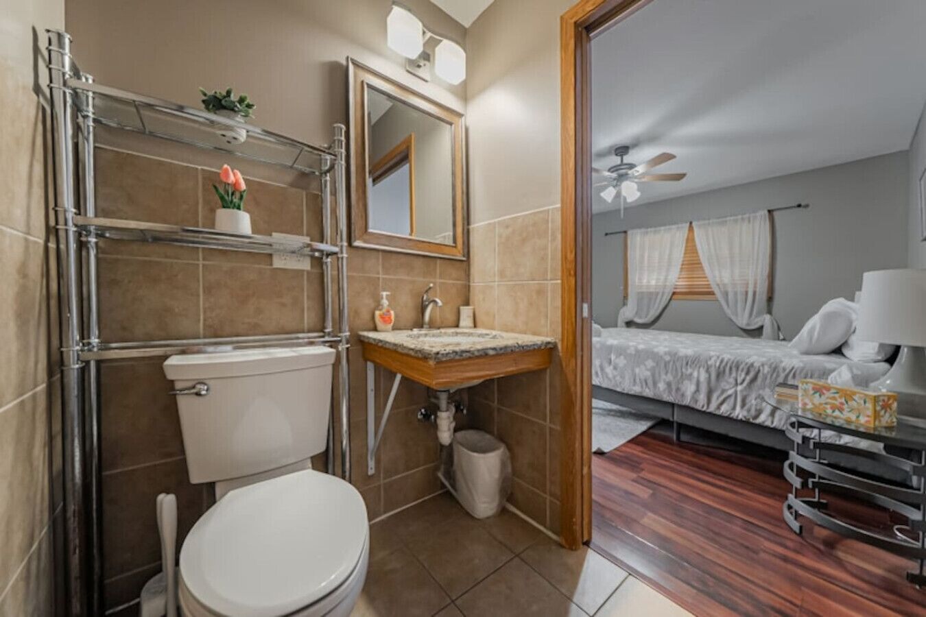 Un baño con inodoro, lavabo y zona de ducha, y un dormitorio con cama y ventana.