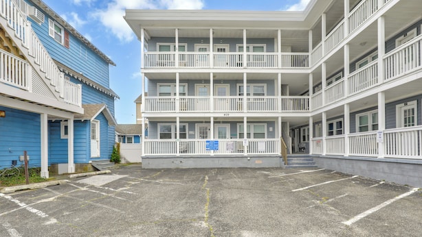 A multi-story hotel with a central courtyard, balconies, and a parking area. - Harbor Breeze 53 by Seaside Vacations & Sales (Ocean City)