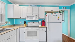 A kitchen with white cabinets, a microwave, a stove, and a refrigerator. - Harbor Breeze 53 by Seaside Vacations & Sales (Ocean City)