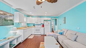 A modern kitchen with white cabinets, a central island, and a ceiling fan. - Harbor Breeze 53 by Seaside Vacations & Sales (Ocean City)