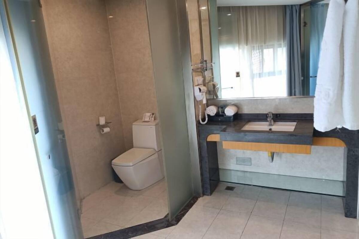 Ein modernes Badezimmer mit Glasdusche, Toilette, Waschbecken mit Spiegel und Handtuchhalter.
