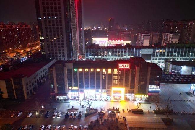 A hotel with a prominent sign, multiple floors, and a parking lot.
