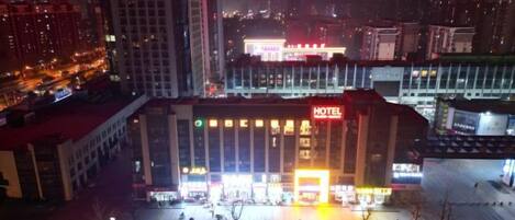 A hotel with a prominent sign, multiple floors, and a parking lot.