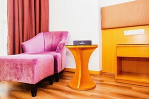 A room with a pink chair, a small wooden table, and a wooden cabinet. - New Baihui Boutique Hotel (Jining)