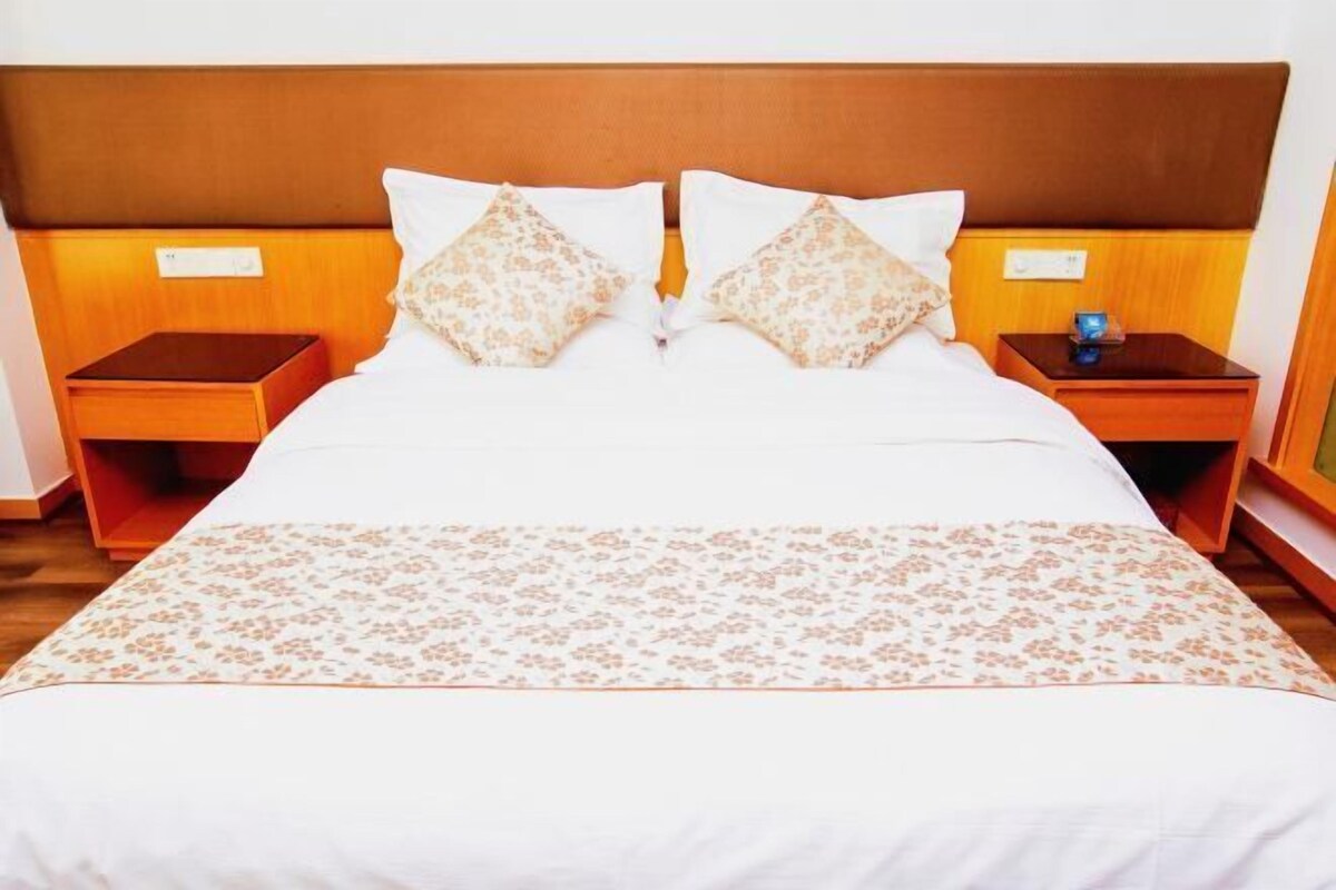 A hotel room with a large bed, two nightstands, and a wooden headboard.