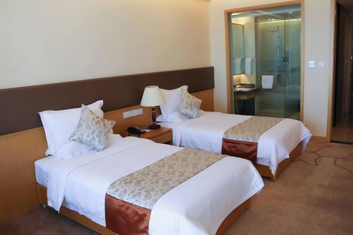 Ein Hotelzimmer mit zwei Betten, einem Nachttisch mit Lampe und einer Duschkabine.