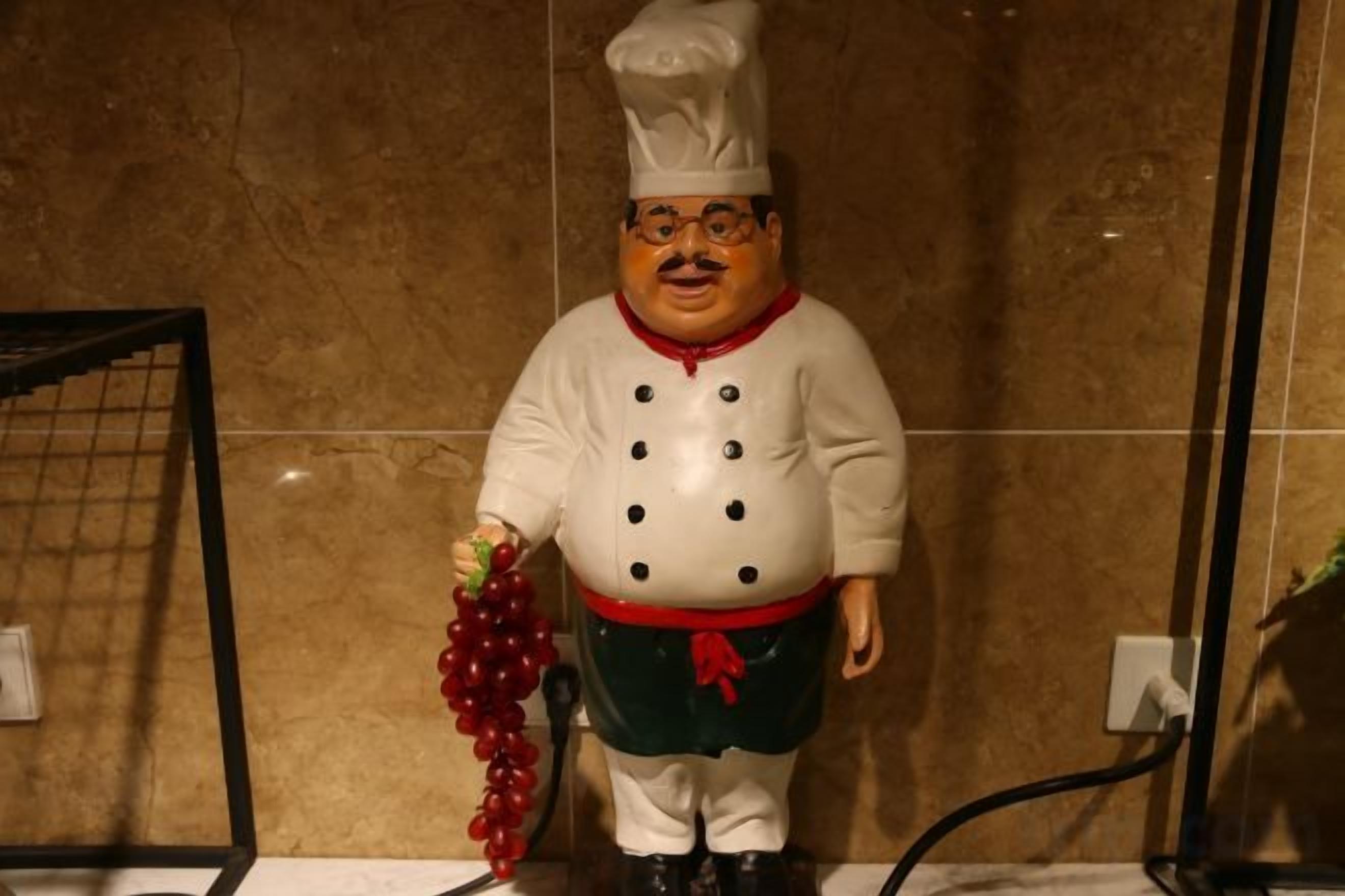 Eine Statue eines Kochs, der einen Weintraubenberg hält.