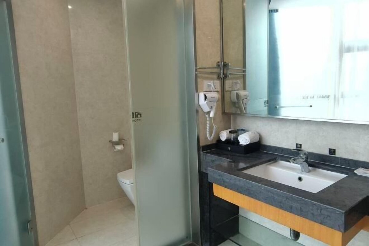 A modern bathroom with a glass shower enclosure, a sink with a dark countertop, and a mirror above the sink.
