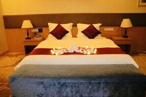 Una habitación de hotel con una cama, dos mesitas de noche y un banco azul.