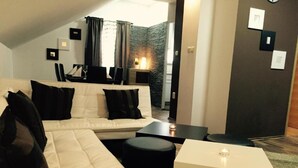 A modern living room with a white sofa, black cushions, a small white table, and a dark floor. - Villa Rubcic (Rakovica)