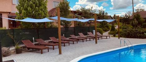 Una piscina al aire libre de temporada, sombrillas, tumbonas