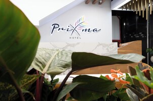 Exterior del Hotel PriKma con un diseño moderno, que incluye un logotipo y un mostrador de recepción.