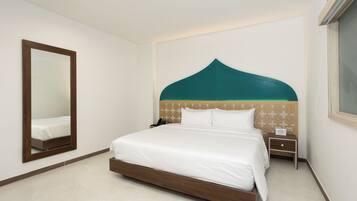 Un dormitorio ordenado con una cama grande, una mesita de noche y un espejo en la pared.