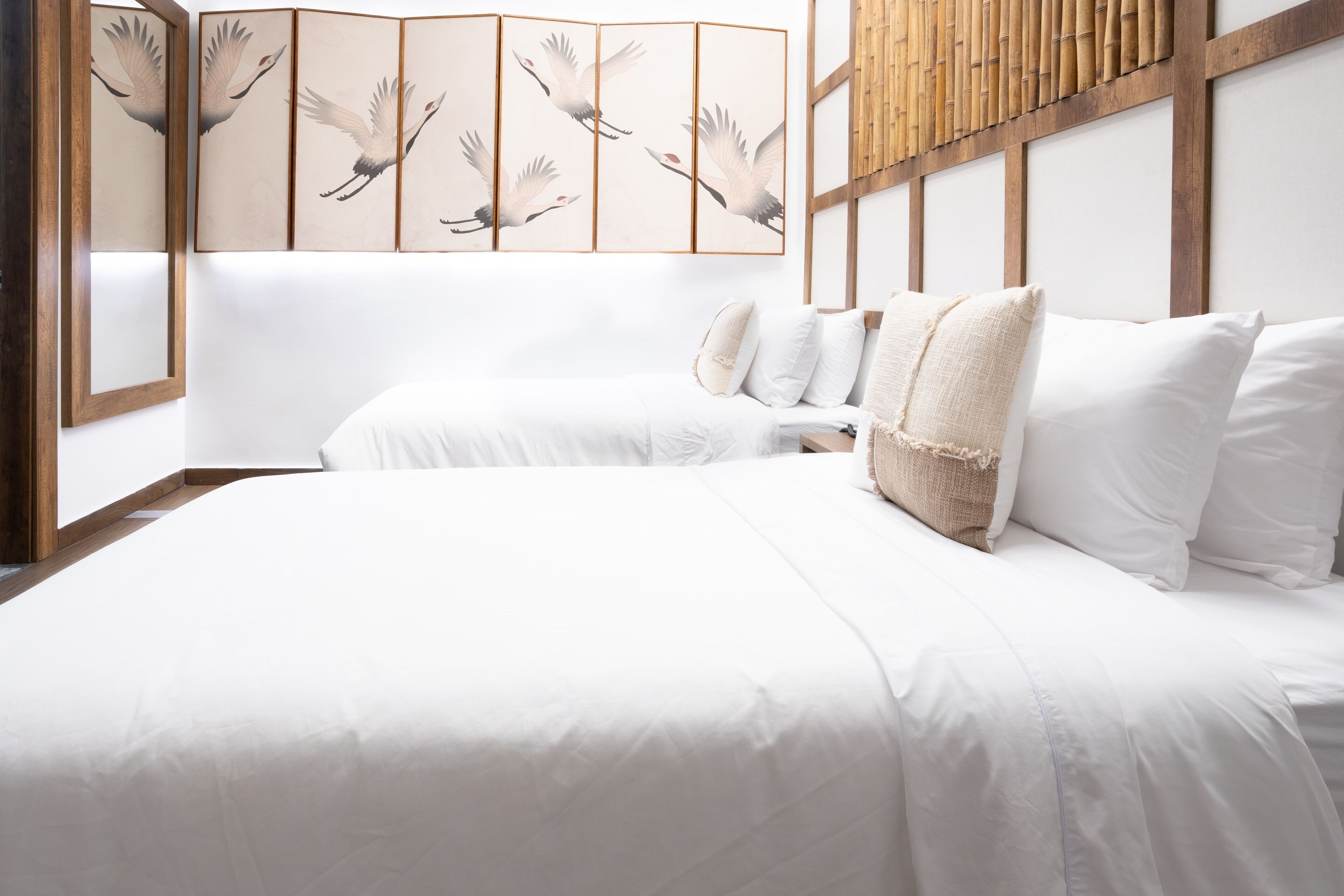 A bedroom with a large bed, white bedding, and a wooden headboard.