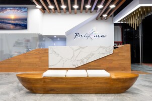 Una zona de recepción con mostrador de madera, pared de mármol y un banco de madera con cojines.