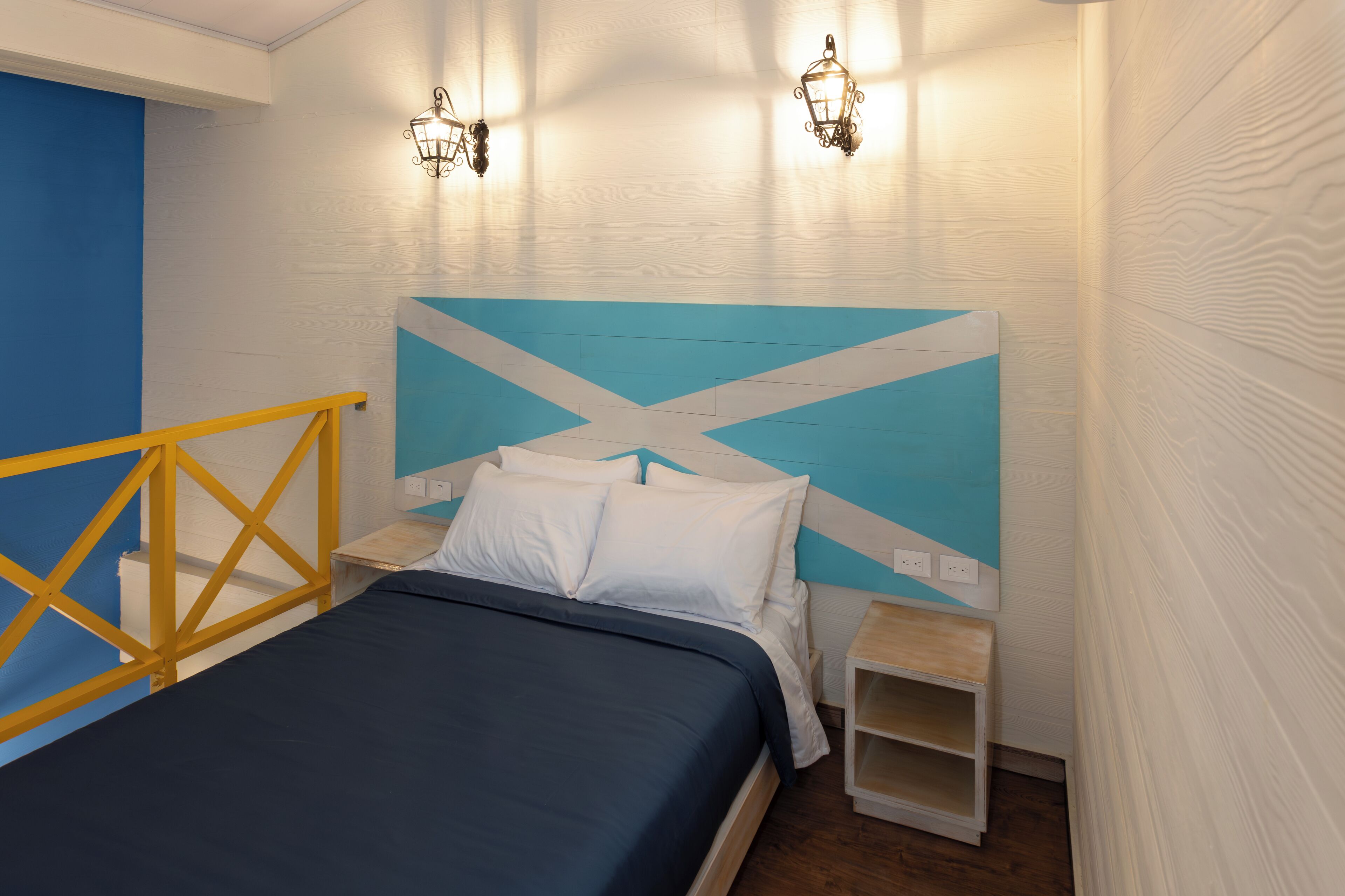 Un dormitorio con cama, mesita de noche y lámpara de pared.