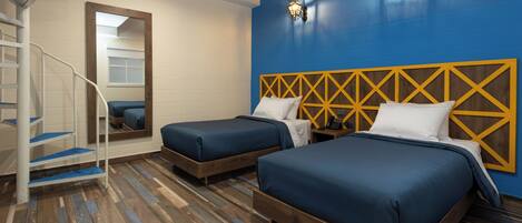 A hotel room with two beds, a wooden headboard, a blue wall, and a spiral staircase.