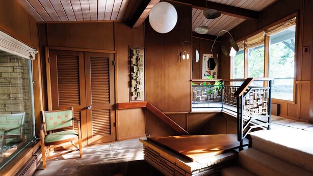 Un intérieur en bois avec un escalier, une chaise et une table.