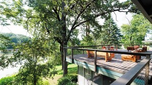 Une terrasse extérieure moderne offrant une vue sur un lac et des arbres.