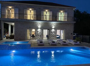 Un bâtiment en pierre de deux étages, doté d’une piscine, d’un espace extérieur aménagé et d’un patio couvert.