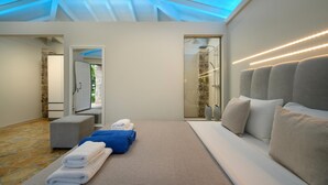 Une chambre moderne dotée d’un grand lit, d’un coin salon et d’une douche à parois de verre.