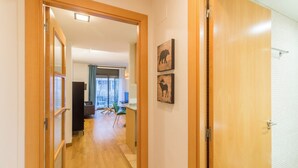 Un pasillo que conduce a una sala de estar con balcón, piso de madera y dos obras de arte con motivos de animales.