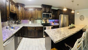 A modern kitchen with dark wood cabinets, stainless steel appliances, and a granite countertop. - Beautifully Remodeled Condo with 1st Floor Access Steps Away from Beach (South Padre Island)