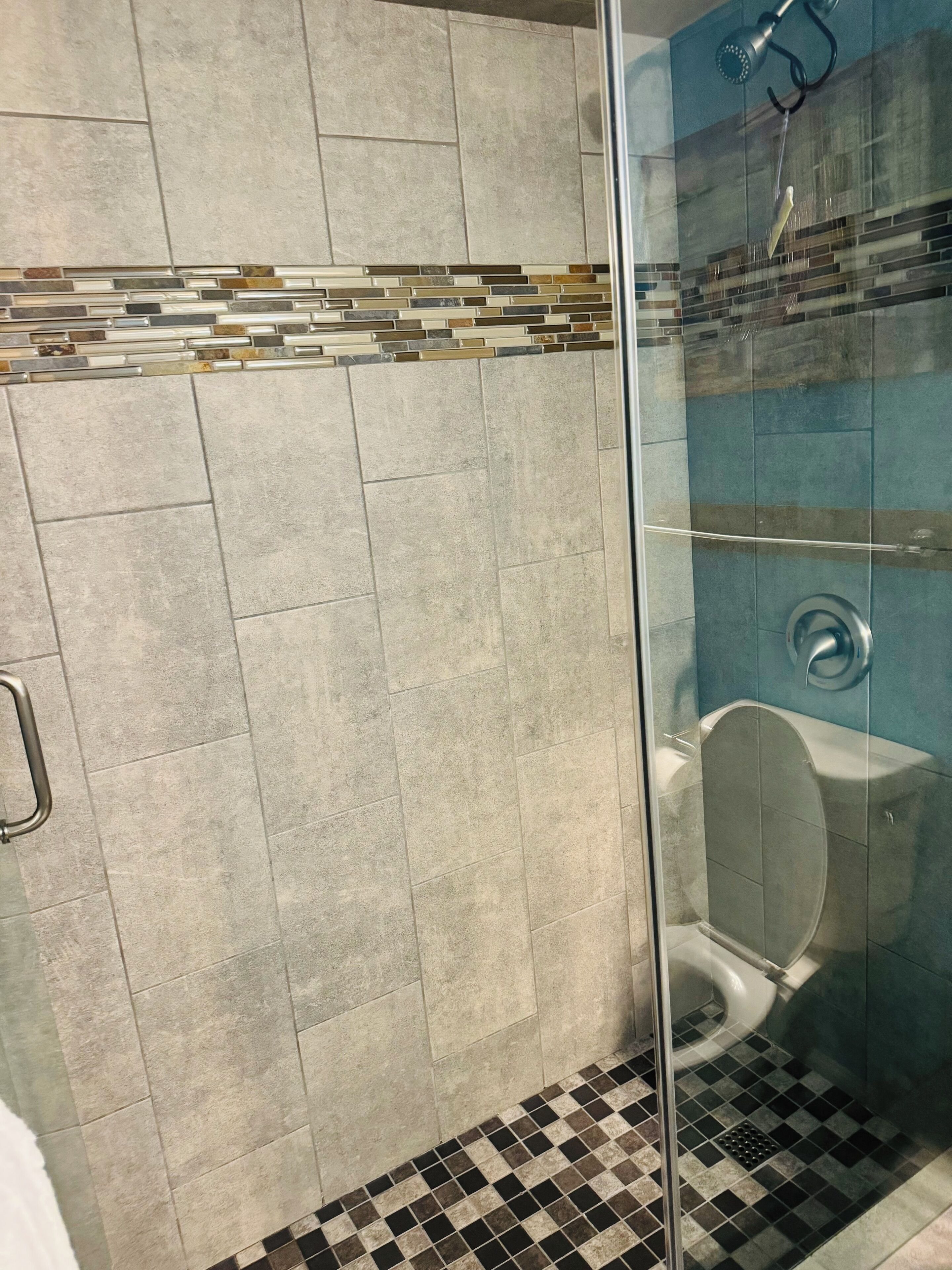 Ein modernes Badezimmer mit Glasdusche, Toilette und Fliesenboden.