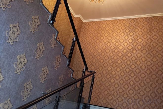 A staircase with ornate railings and patterned wallpaper.