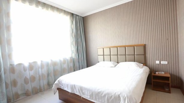 Une chambre moderne avec un grand lit, une table de chevet et une fenêtre avec des rideaux.