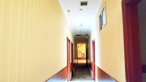 A long, narrow hallway with doors on both sides, leading to a room at the end. - Qian Guoxin Dingsheng Hotel (Songyuan)