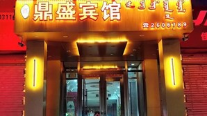 L’entrée d’un hôtel, avec un panneau lumineux, un comptoir d’accueil et des portes en verre.