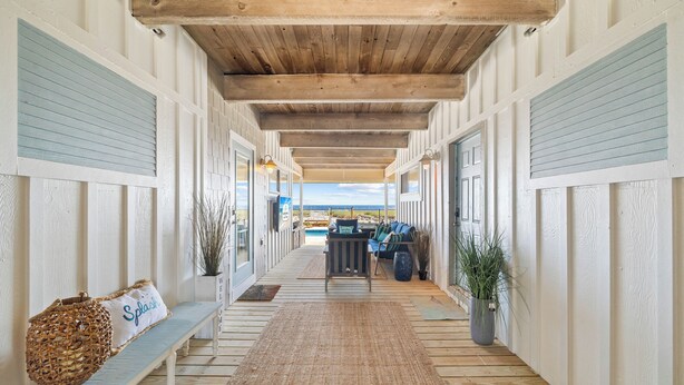 A covered corridor with a wooden ceiling, benches, and potted plants. - Starfish Wishes: Beachfront Duplex Unit, Great location, remodeled, Pet Friendly (St. George Island)