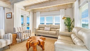A spacious living room with a large sofa, striped armchairs, and a wooden coffee table. - Starfish Wishes: Beachfront Duplex Unit, Great location, remodeled, Pet Friendly (St. George Island)