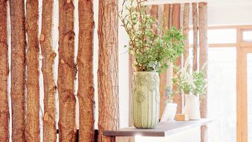 Un mur en bois avec des lattes verticales et une plante en pot posée sur une étagère.