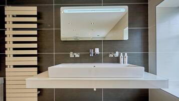 A modern bathroom with a large rectangular sink, a mirror above it, and a towel rack to the left.