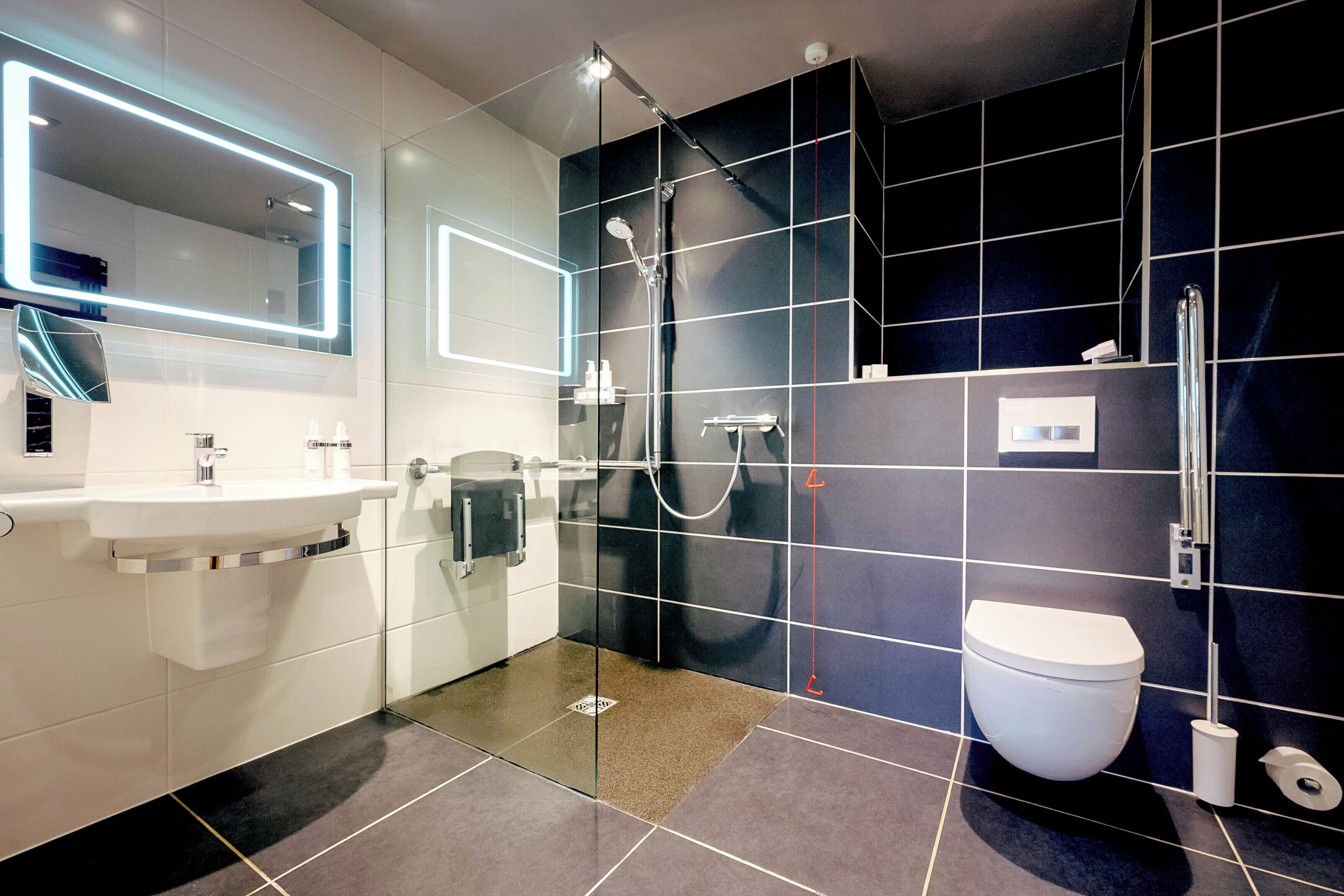 A modern bathroom with a glass-enclosed shower, a white sink, and a toilet.