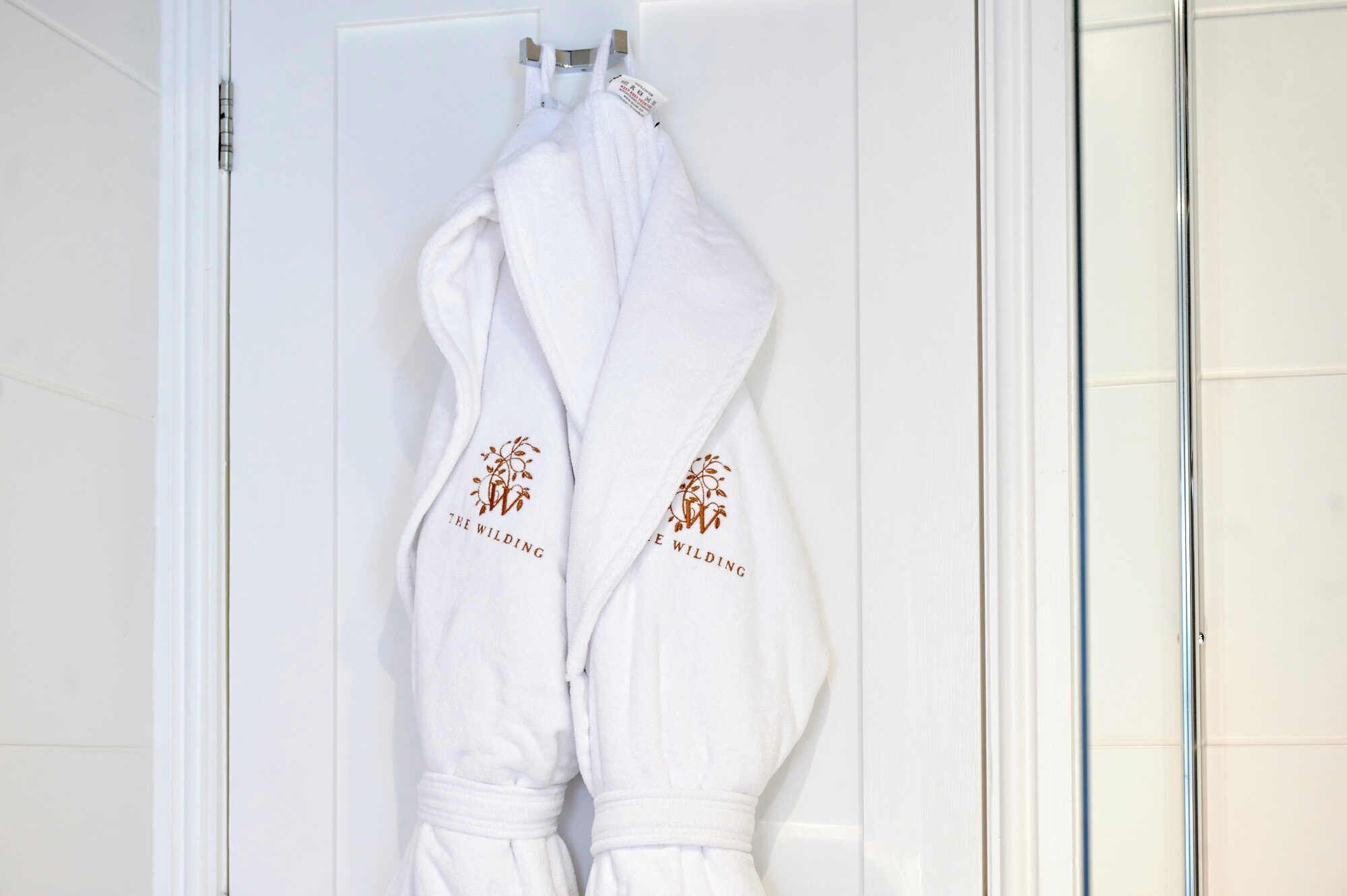 Deux robes blanches sont suspendues à la poignée d’une porte.
