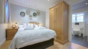 A bedroom with a bed, bedside tables, a wardrobe, and a bathroom visible through an open door.