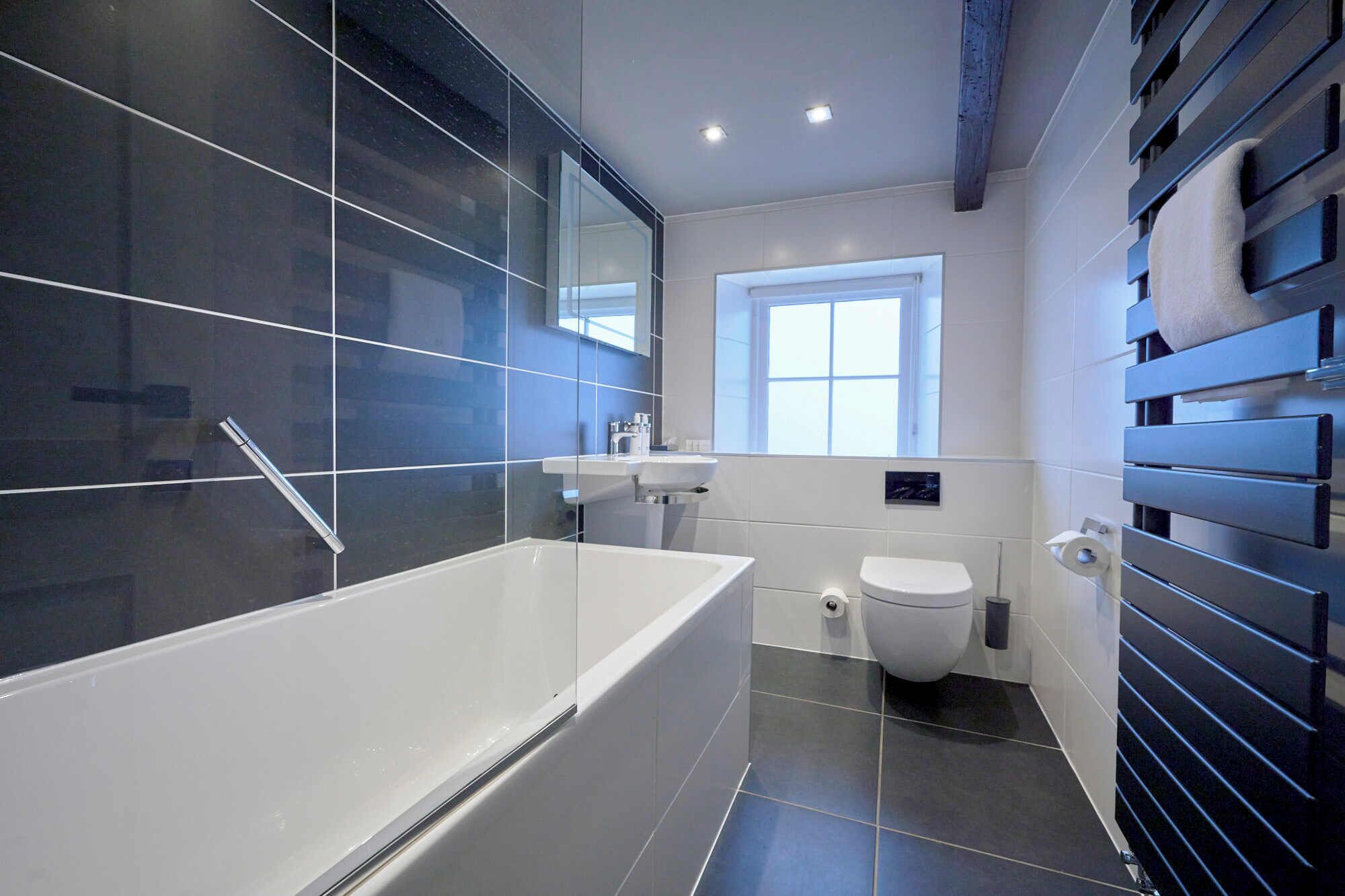 A modern bathroom with a bathtub, toilet, and sink.