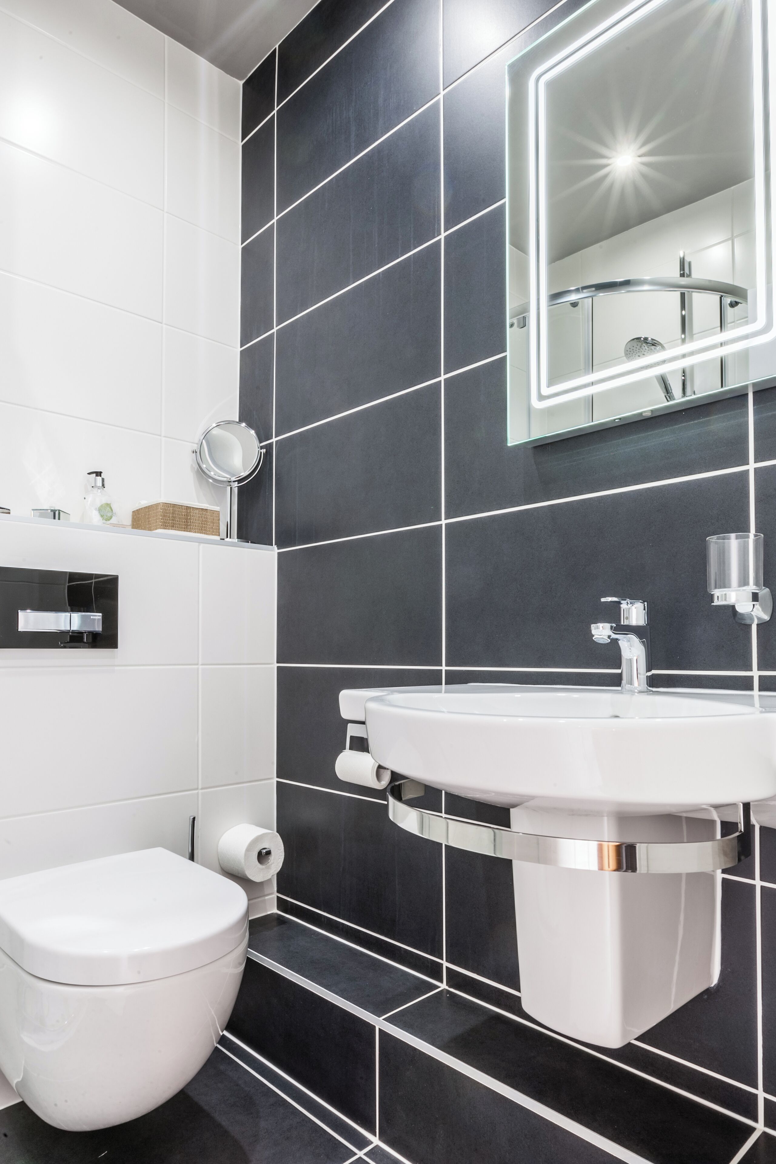 A modern bathroom with a white toilet, a white sink, and a mirror with LED lighting.
