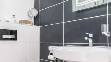 A modern bathroom with a white toilet, a white sink, and a mirror with LED lighting.