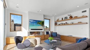 A modern living room with a fireplace, comfortable seating, and a large TV.