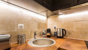 A modern kitchen with a stainless steel sink, wooden countertop, and a coffee maker.