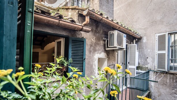 A courtyard with a rustic building, air conditioning units, and a potted plant. - Estate4home - Trevi Fountain Apartment (Rome)