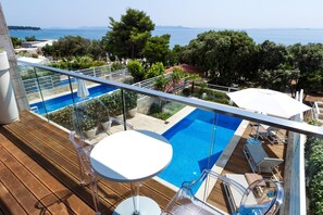 A balcony with a glass railing overlooking a swimming pool and a view of the sea. - Villa Magnolia Zadarvillas (Zadar)