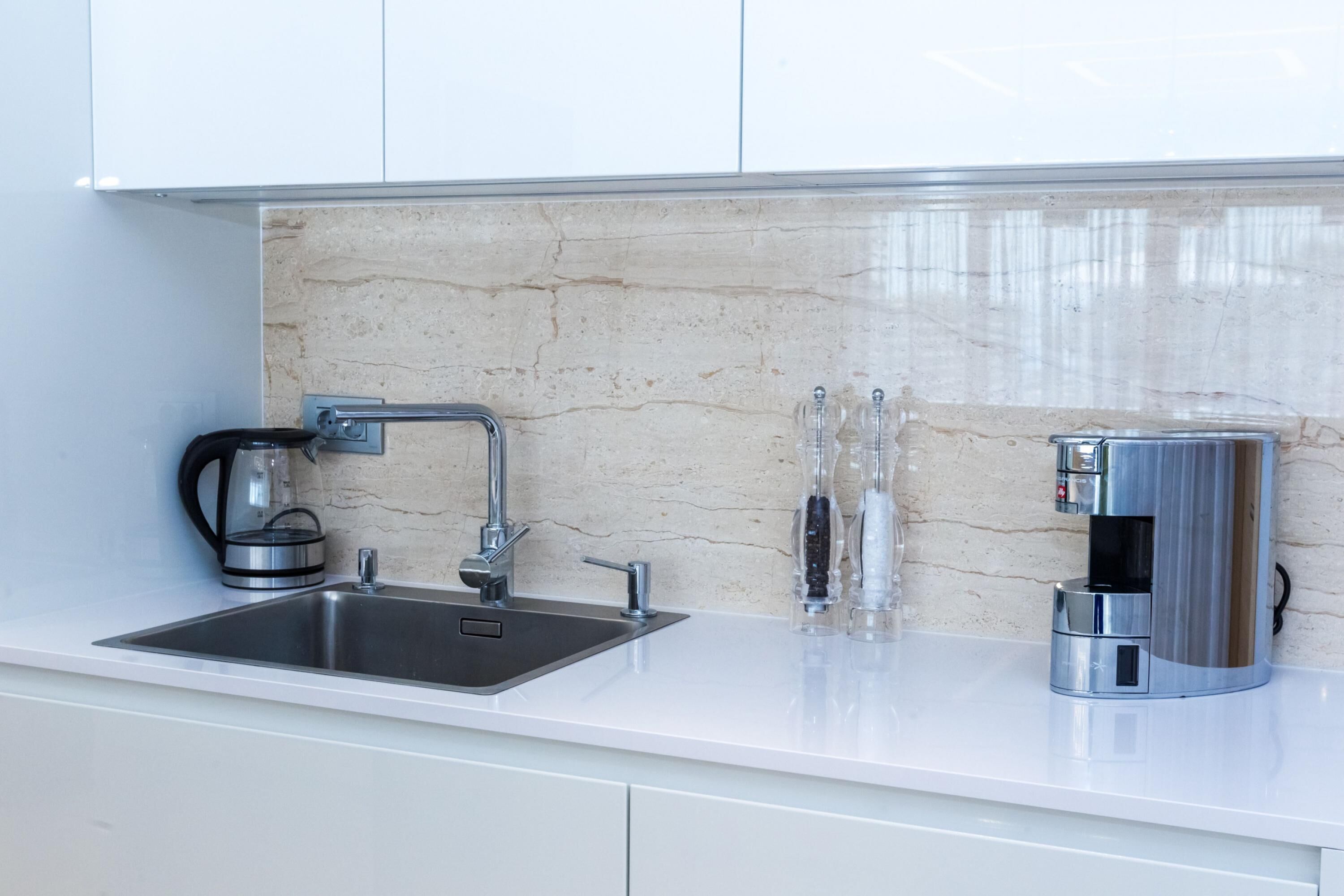 A modern kitchen with a stainless steel sink, a coffee maker, and a glass carafe.